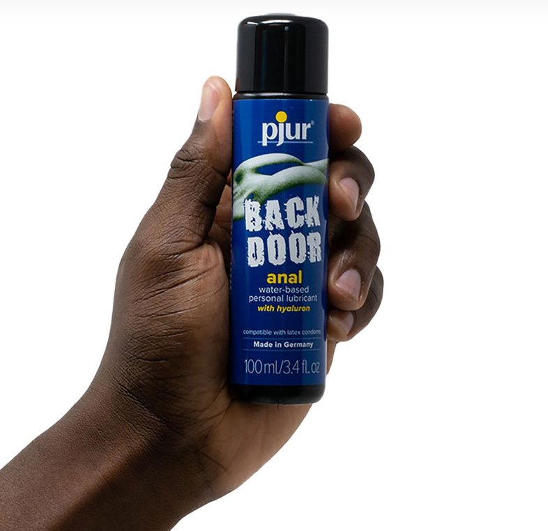 A person holds a 100ml bottle of Pjur Back Door Anal Water-Based. The bottle looks much slimmer than a seltzer can, but it looks to be similar in height. It fits comfortably in the person's hand. | Kinkly Shop