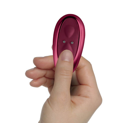 A person's hand holds the remote for the Rocks-Off Ruby Glow Blush. The remote has two buttons on it as well as two magnetic charging ports to recharge the remote. | Kinkly Shop