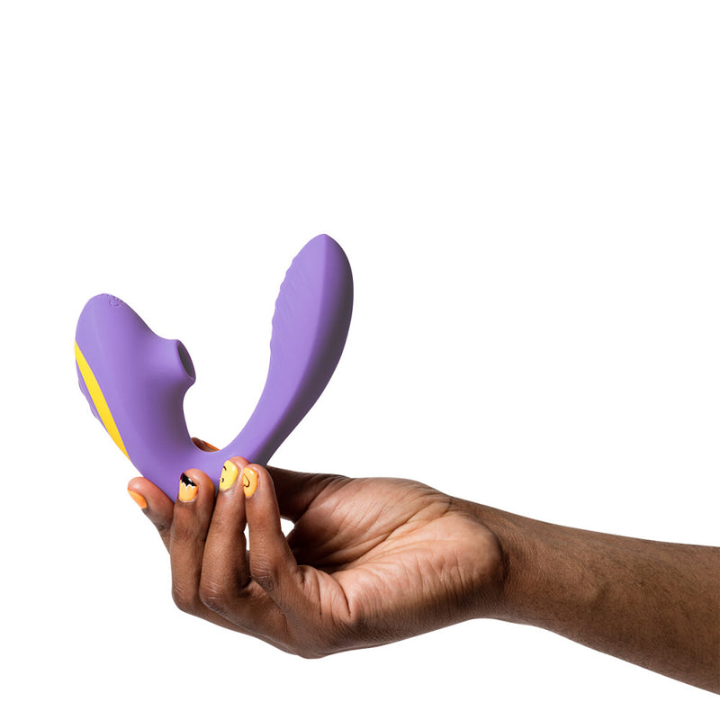 A hand holds the ROMP Reverb up against a white background. The toy has a very right angle/U-shaped design to help hit the clitoris and the g-spot at the same time. The g-spot dildo end has texturing on it. | Kinkly Shop 
