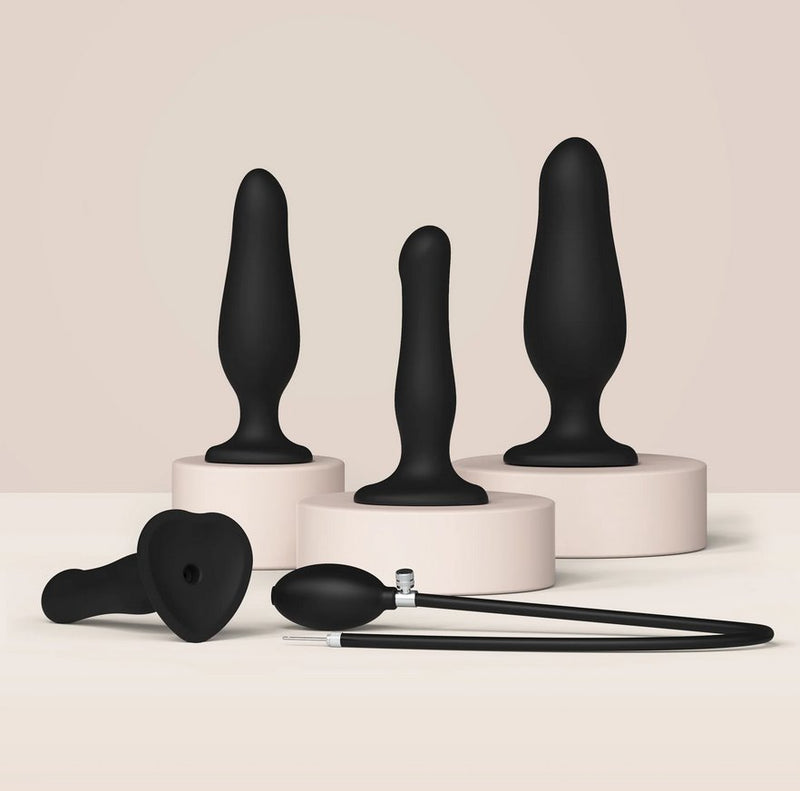 Three different Strap-on-Me Inflatable Dildo Plugs shown next to each other. Each plug has a different level of inflation, showing the thinnest, thickest, and middle-of-the-road thickness that the Strap-on-Me Inflatable Dildo Plug can obtain. The inflation bulb and tube are shown in the foreground, detached from the base of any of the dildo plugs. | Kinkly Shop