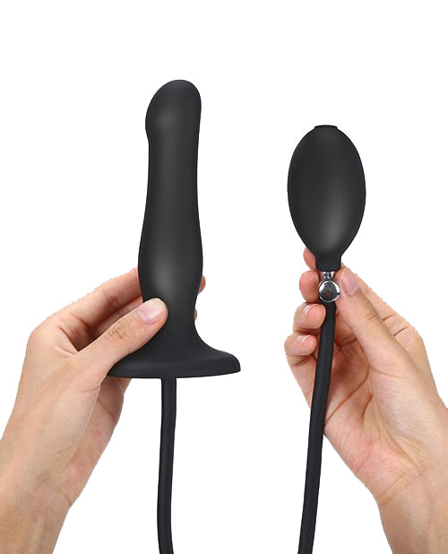 Two hands show the Strap-on-Me Inflatable Dildo Plug against a white background. One hand is holding the plug dildo itself while the other hand is holding up the inflatable bulb with quick-release valve. | Kinkly Shop