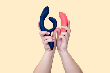 A hand holds up the We-Vibe Nova 2 next to the We-Vibe Melt. The Melt is much, much smaller in length than the rabbit vibrator next to it. | Kinkly Shop