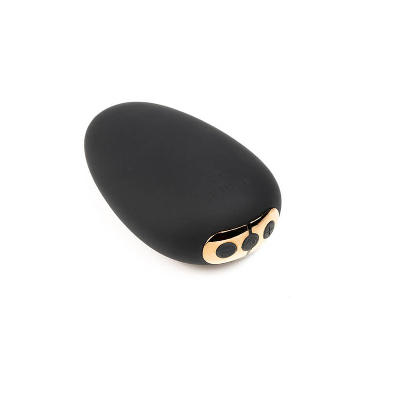 Close-up of the Je Joue Naughty Collection Mimi vibrator. The vibrator looks like a soft, smooth, pebble in black silicone with a rose gold control panel on one tip of the vibrator. | Kinkly Shop