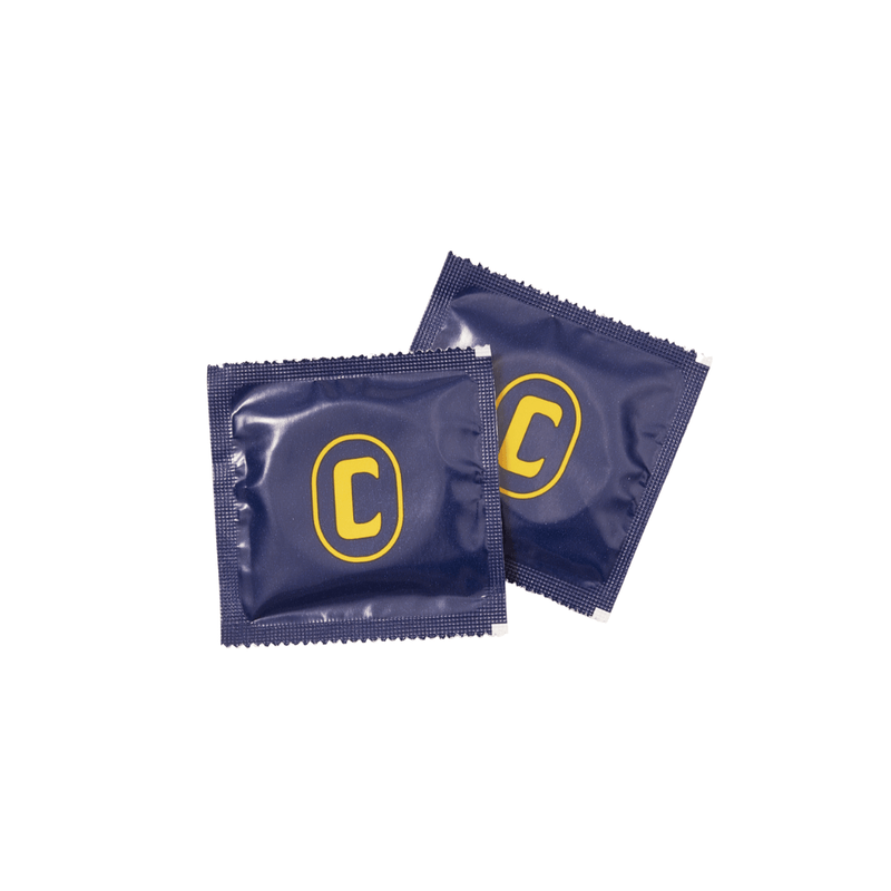 Two of the individually-wrapped Champ Slugger Fit XL Condoms sit out against a white background. The square wrappers are dark blue in color with a golden "C" in the center of them. | Kinkly Shop