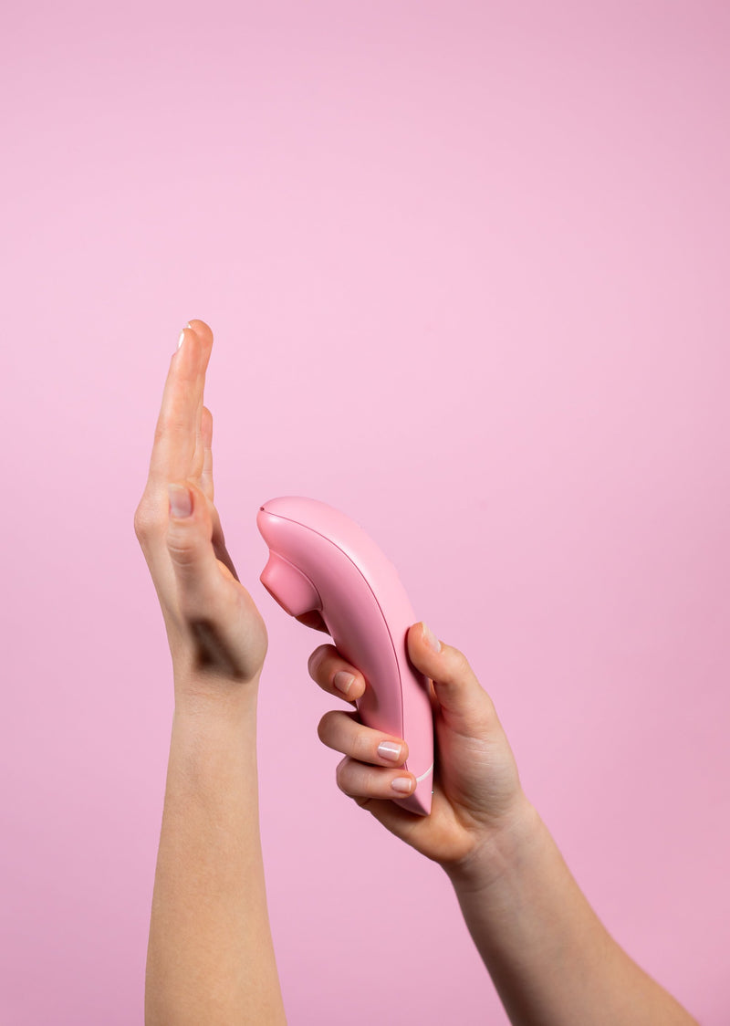 A hand holding the Womanizer Premium Eco friendly sex toy is almost touching an open palm to illustrate the Smart Silence concept the vibrator is equipped with | Kinkly Shop