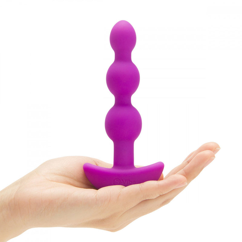 The b-Vibe Triplet Anal Beads being placed on top of a hand to show its full size and design | Kinkly Shop