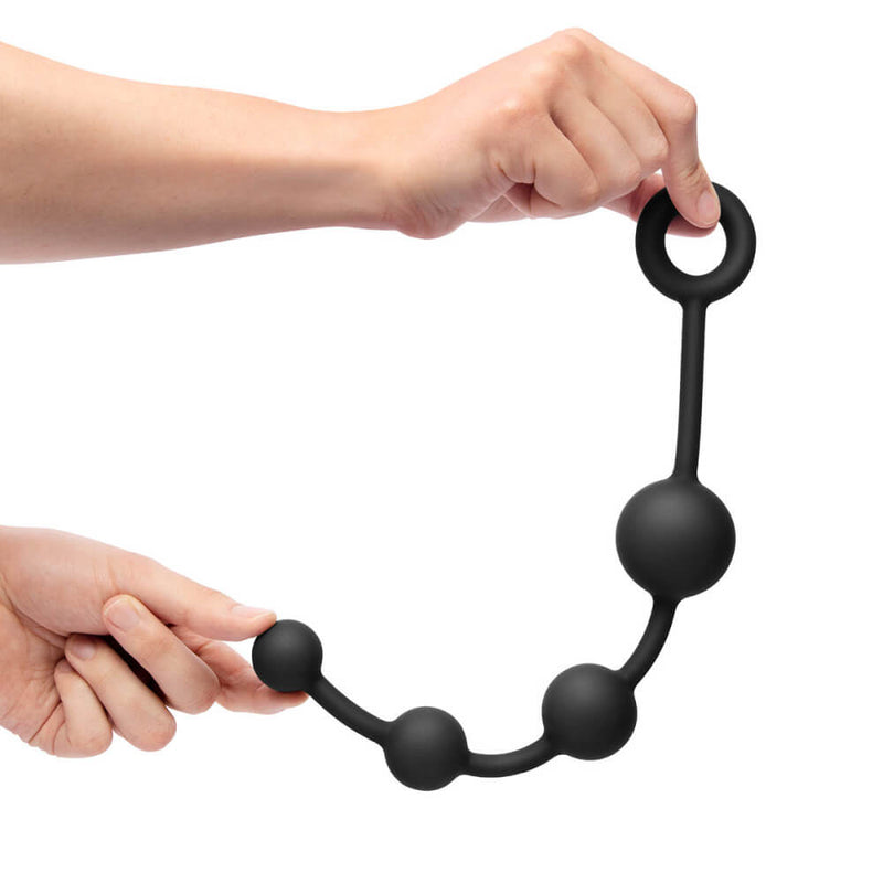 A hand holds up the anal beads included in the b-Vibe mASSter's Degree Anal Set. They are very long and large compared to standard anal beads. The largest bead looks like it may be as thick as four fingers. | Kinkly Shop