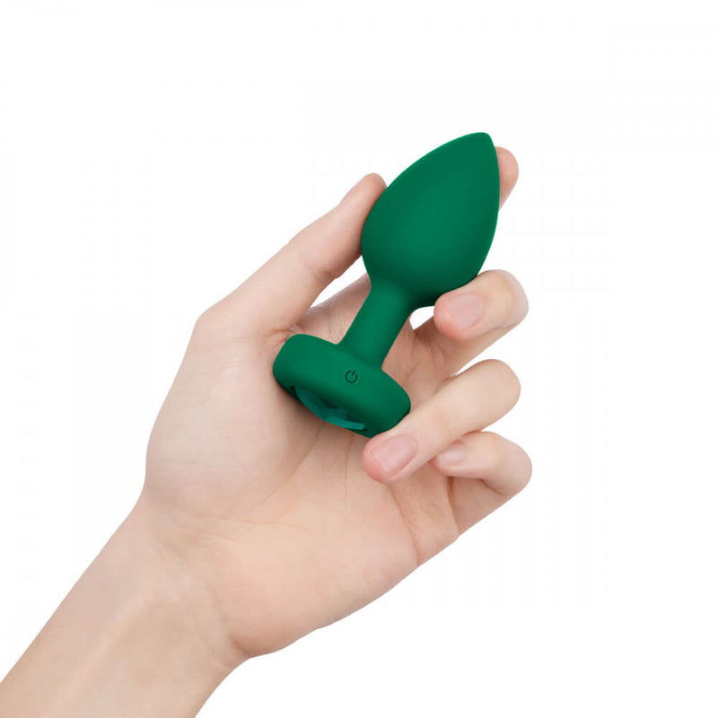 A hand grasps the b-Vibe Vibrating Jewel Remote Control Butt Plug. It shows the size of the plug. It goes from near the tip of the person's extended pointer finger to the base of their thumb. | Kinkly Shop