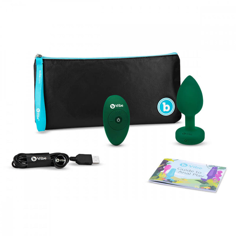 Everything that's included with the b-Vibe Vibrating Jewel Remote Control Butt Plug. This includes the plug itself, the remote control, the high-quality zippered pouch, the USB charging cable, and the b-Vibe Guide to Anal Play booklet. | Kinkly Shop