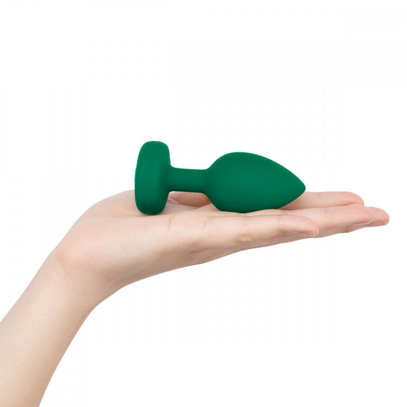 A hand holds the b-Vibe Vibrating Jewel Remote Control Butt Plug while laying flat. It shows the size of the plug. | Kinkly Shop