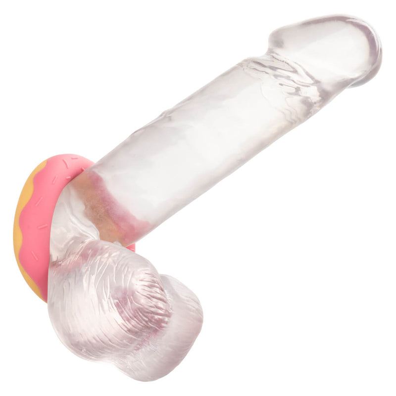 The Naughty Bits Dickin' Donuts is worn at the base of a dildo. The dildo has testicles, and the cock ring is shown being worn underneath the testicles as well as the shaft. | Kinkly Shop