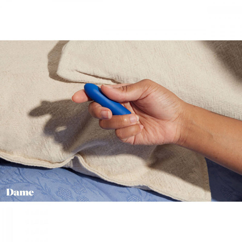 A hand holds the Dame Zee bullet vibrator. The vibrator is about the size of a finger, and it would disappear into the person's hand if they fully wrapped their fingers around it. | Kinkly Shop