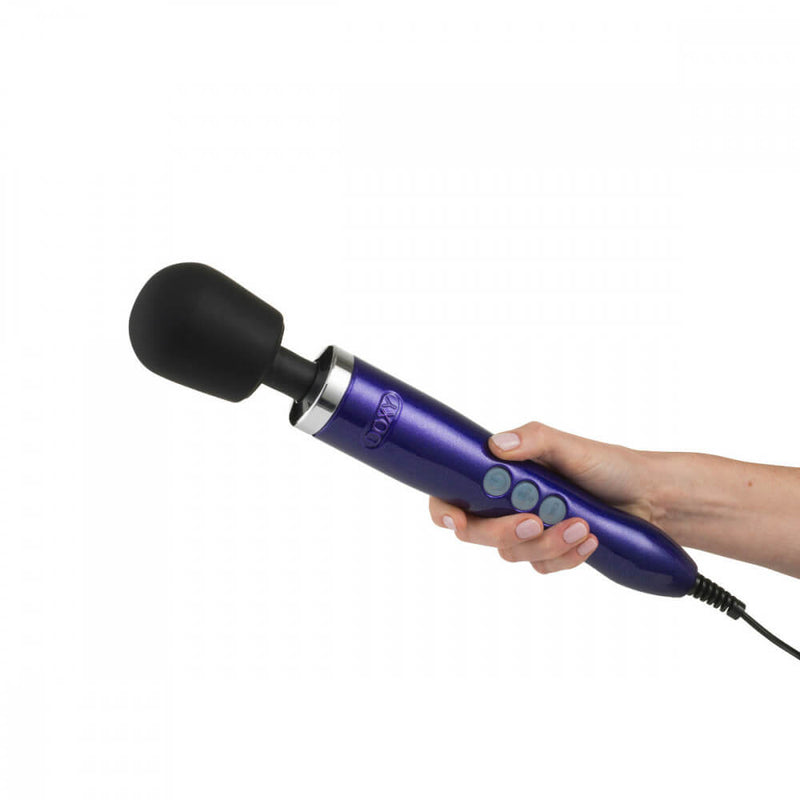 A hand is holding the Doxy Die Cast massager. The massager is large compared to the hand, and the handle only covers one-half of the length of the handle of the Doxy vibrator. The buttons are easily-accessible by the thumb of the hand that's holding the Doxy vibrator. | Kinkly Shop