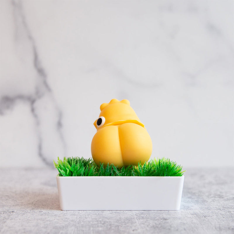 The Emojibator Chickie rests in a small bed of "grass" with its butt facing towards the camera. It has a bubble butt with a clear line and cheek curves to boot. | Kinkly Shop