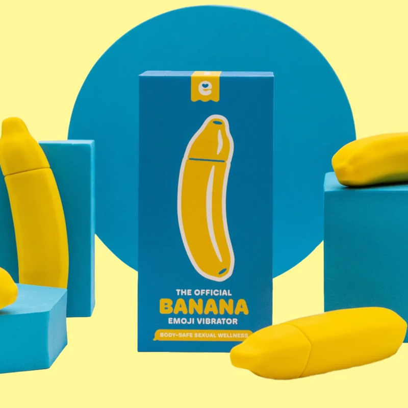 Packaging for the Emojibator Banana. The box is surrounded by a bunch of Banana vibrators with a yellow and blue design that looks really playful and fun. | Kinkly Shop
