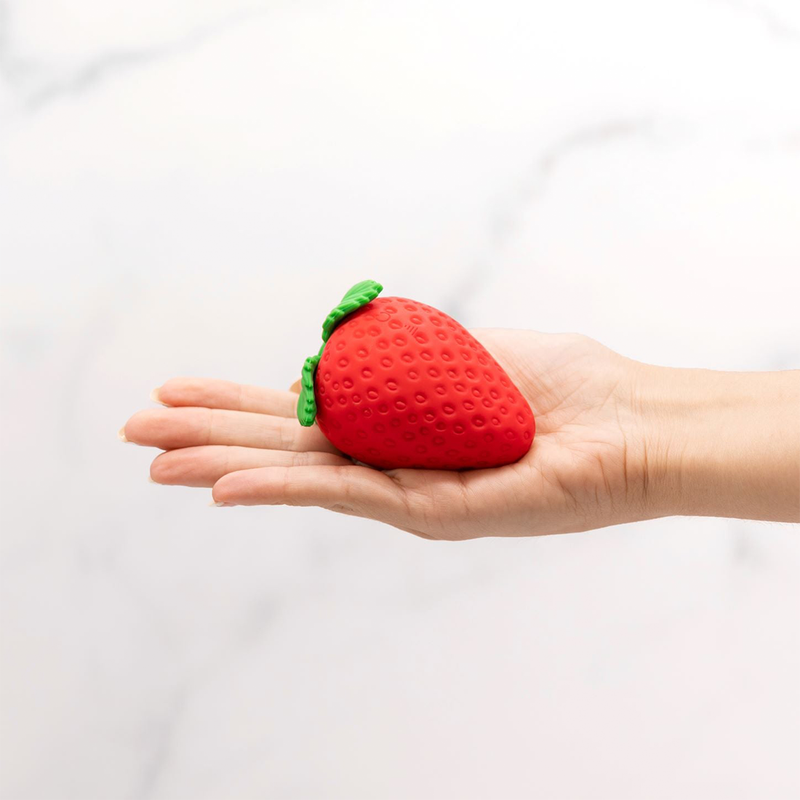 The Emojibator Strawberry placed in the palm of someone holding their hand open. The vibrator is about the size of the person's palm. It's about the size of an extra-large biological strawberry. | Kinkly Shop