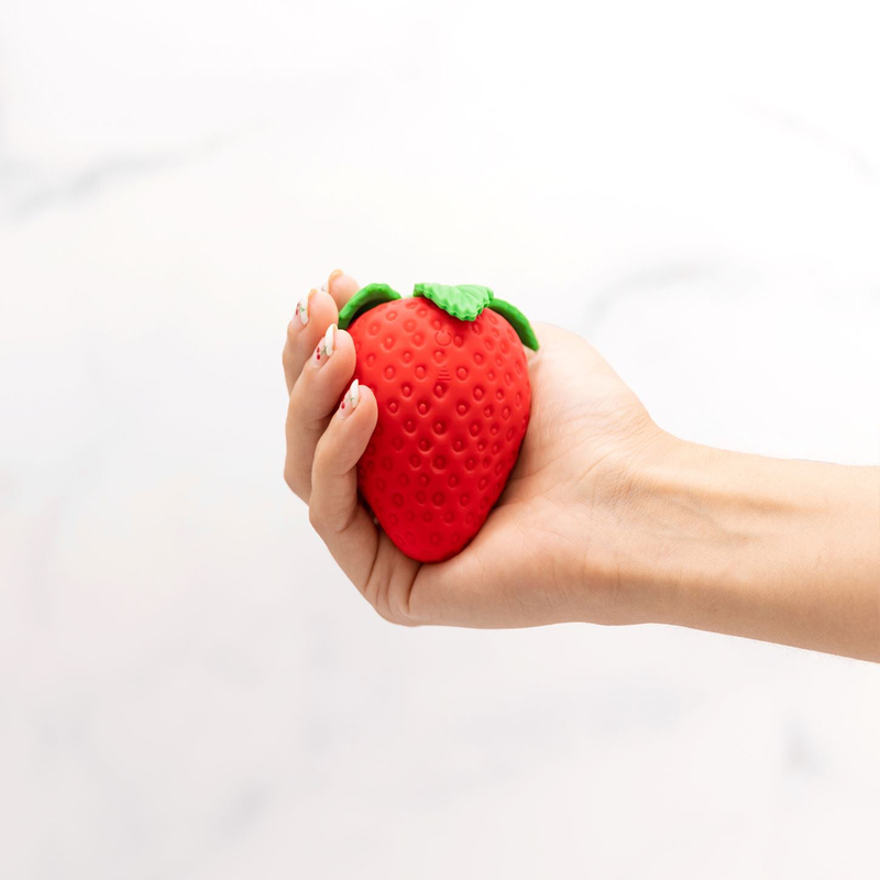 A hand holds the Emojibator Strawberry, cradling their fingers around the width of the Strawberry. Cradling the vibrator in their hands, they are unable to close their fingers anywhere near around the Strawberry. It's a thick toy. | Kinkly Shop
