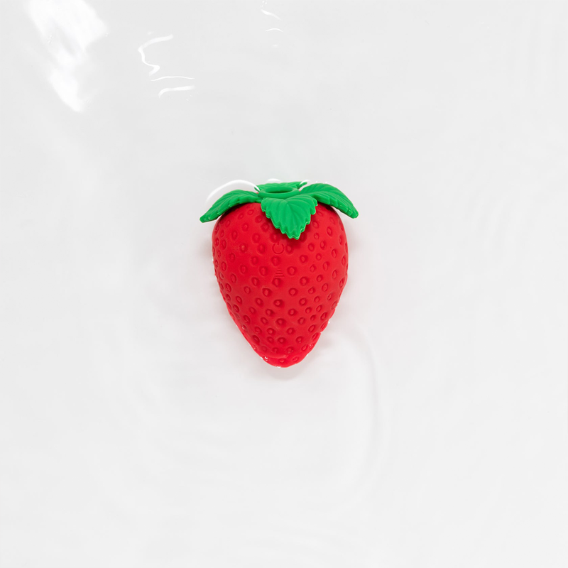 The Emojibator Strawberry rests in front of a plain white background. The Strawbery red and leaf green are very vibrant, and they really stand out. | Kinkly Shop