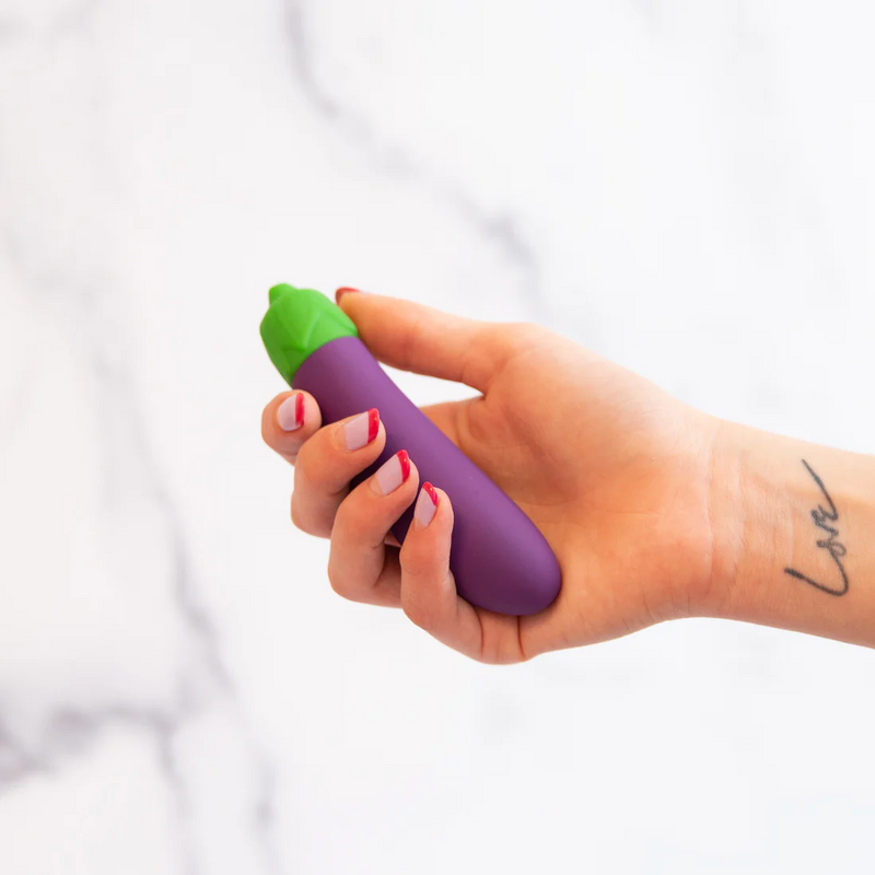 A person's hand holds the Emojibator Eggplant. Their fingers curl around it easily, and it cradles comfortably within their hand. | Kinkly Shop