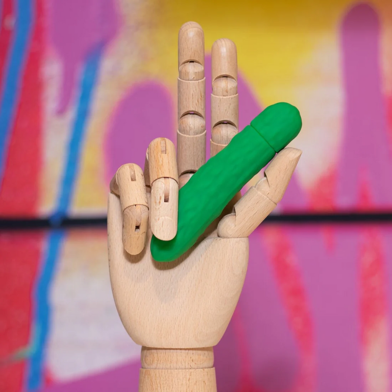 An art model hand holds the Emojibator Pickle in it. | Kinkly Shop