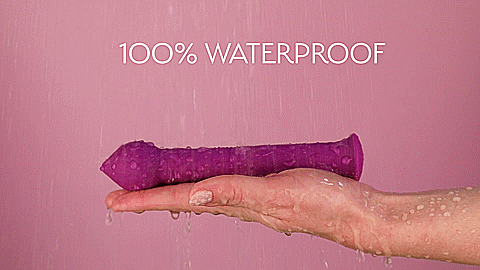 A GIF showing the FemmeFunn Diamond Wand being held up by a person's flat hand. The hand is holding the vibrator underneath a violent rainstorm of water. The text on the GIF reads "100% Waterproof". | Kinkly Shop