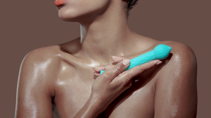 An oiled, nude person holds the FemmeFunn Diamond Wand in front of them. It is clearly longer than their hand, and it is about as long as the distance between the holder's clavical and the shoulder joint. The FemmeFunn Diamond Wand is noticably thicker than a single finger. | Kinkly Shop