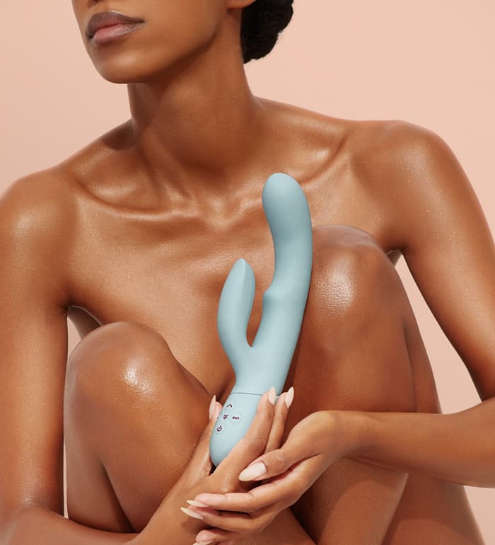 A naked person holds the FemmeFunn Balai in front of their crossed knees. The FemmeFunn Balai doesn't look small, and it looks to be about the length of 3/4th's of the person's forearm. | Kinkly Shop