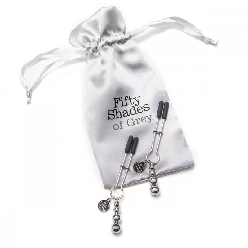 The Fifty Shades of Grey Pinch Nipple Clamps laying out on top of the Fifty Shades of Grey grey, drawstring storage bag. | Kinkly Shop