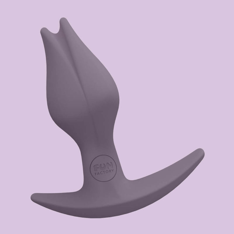The Fun Factory Bootie Fem in Dark Taupe up against a purple background. The "tulip" design of the tip is very obvious in this photo as well as the Fun Factory logo etched into the base. | Kinkly Shop