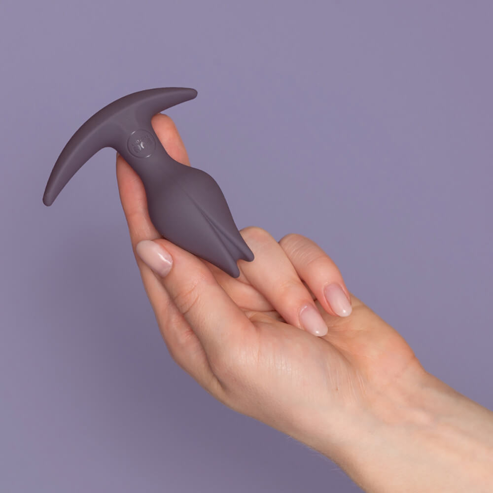 A person holds the Fun Factory Bootie Fem in their hand. The toy looks relatively small, and it can easily be held by two fingers with the thumb to stabilize. It is not as wide as two fingers, and it is barely long enough to touch the edge of the palm. | Kinkly Shop