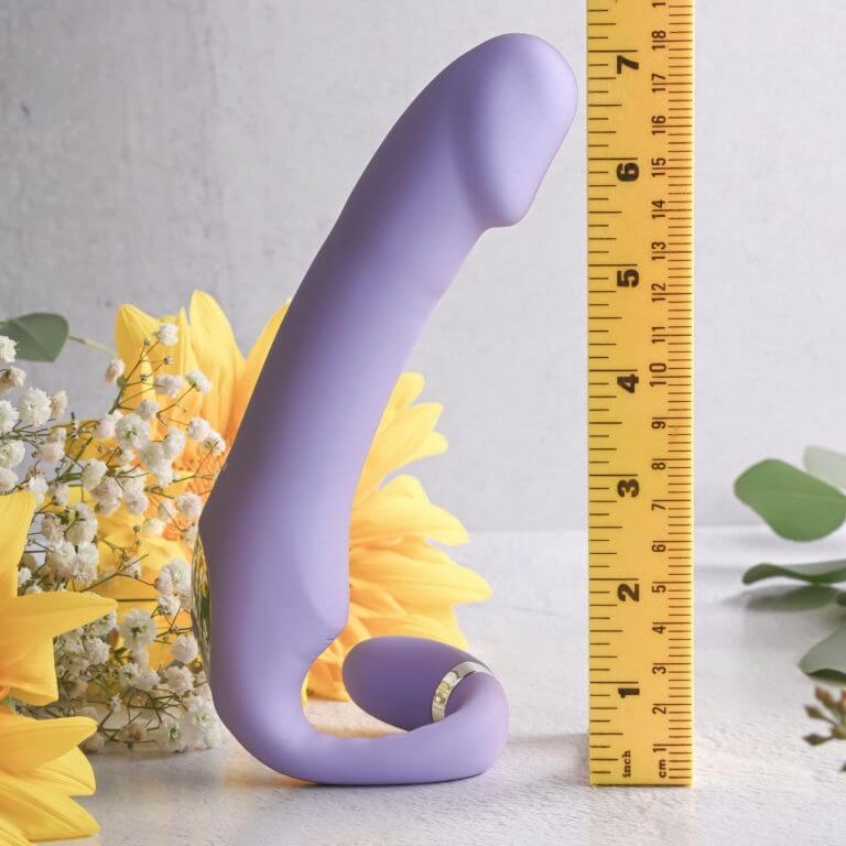 The Gender X Orgasmic Orchid next to a construction-style measuring tape. The dildo-looking end is a total height of slightly over 7" according to the image. | Kinkly Shop