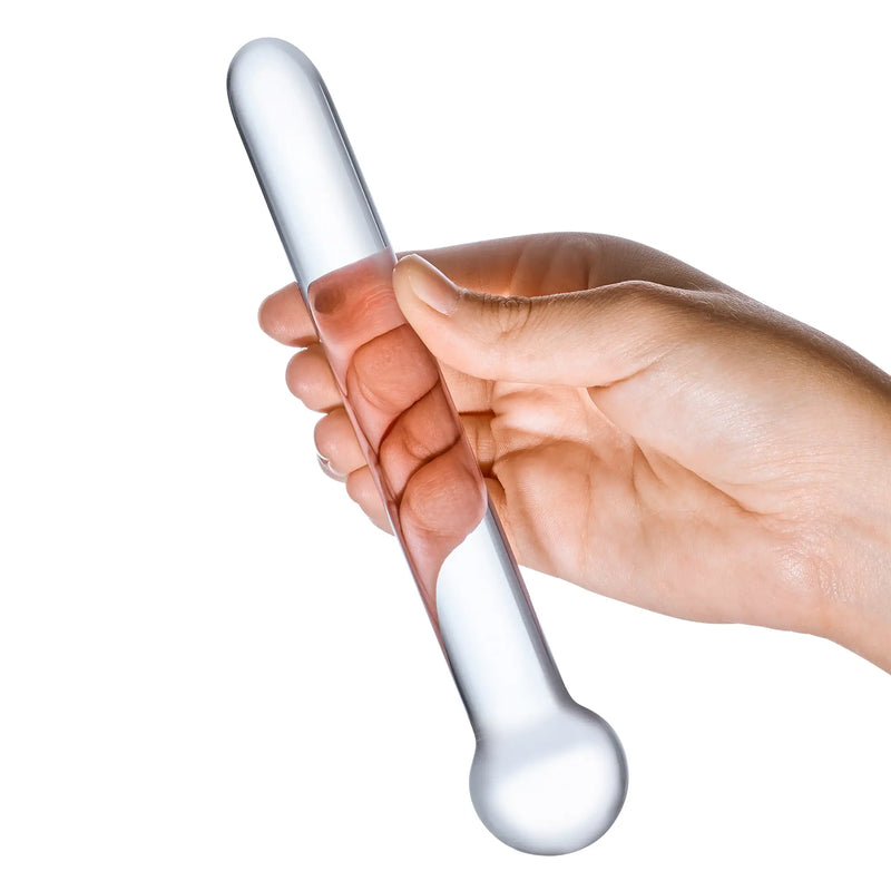 A hand holds the Glas 7" Straight Glass. This showcases the dildo's see-through design and the slender size of the dildo. The dildo looks to be slightly thinner than two fingers held together. | Kinkly Shop