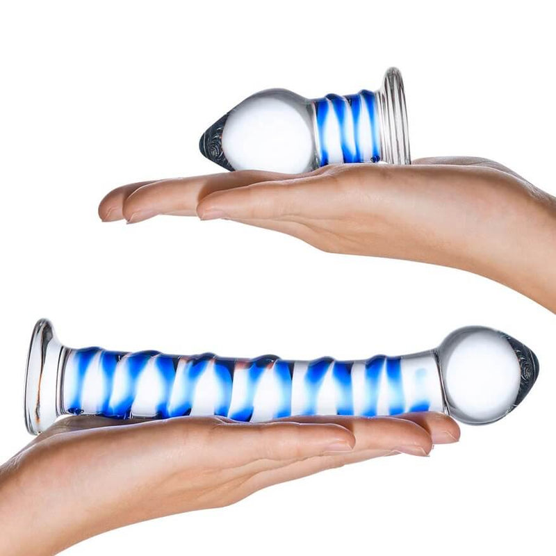 Two hands are splayed out flat. On each hand is a toy included in the 2-piece Glas Double Penetration Kit. The dildo is much longer than the person's hand, extending past the tip of their fingers. The butt plug is much shorter and is only about the length of their palm. | Kinkly Shop