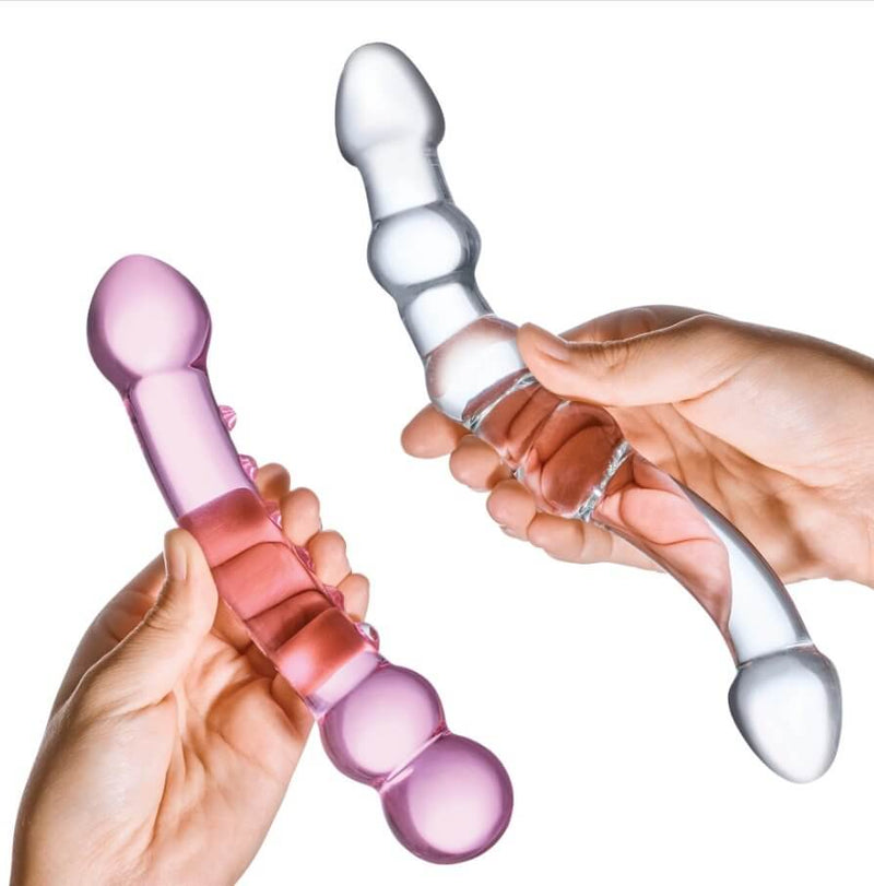 Two hand grasp the middles of each of the two included GLAS Double Pleasure Set dildos. This allows a usable end to protrude forward and backward from each dildo to showcase the four different sensations these toys can be inserted to provide. | Kinkly Shop