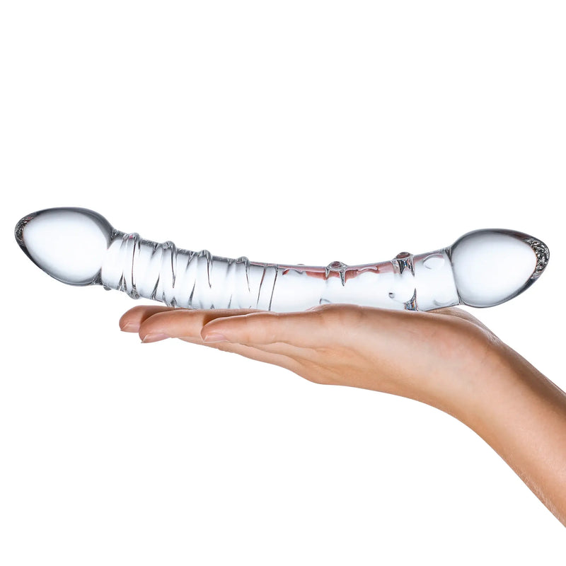 A flat palm holds up the Double Trouble Glass Dildo. The dildo is clearly longer than the person's palm, and it has two separate textures on each side of the dildo. | Kinkly Shop