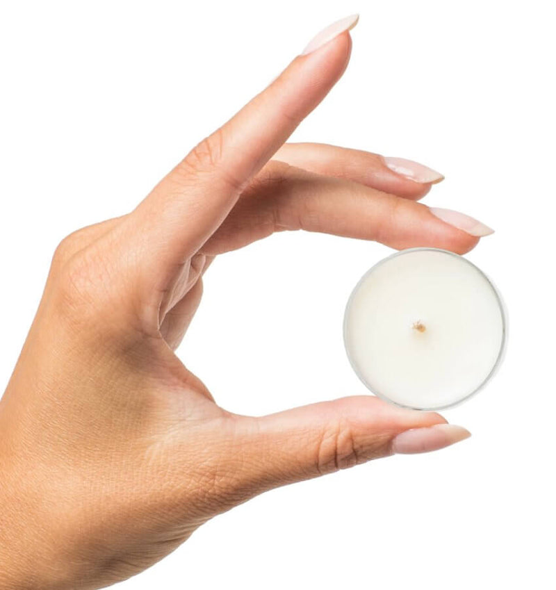 A hand holds the tea light candle included within the Kama Sutra Getaway Kit. It's a standard tealight candle size. | Kinkly Shop