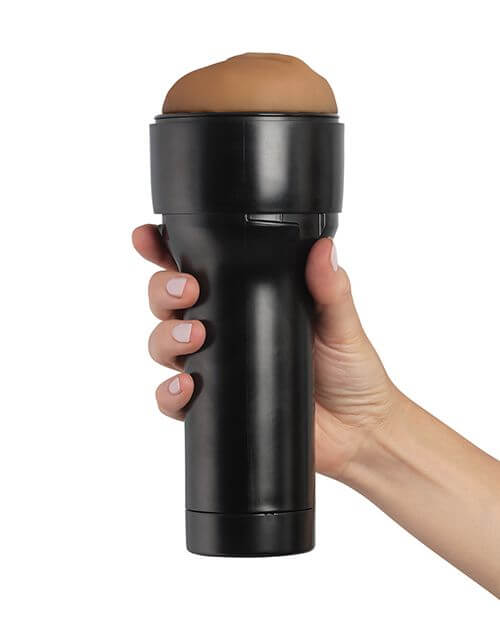 KIIROO RealFeel Generic Vulva in Light Brown. A hand is wrapped around the base of the stroker. The casing of the stroker offers a lot of space for the hand to rest, and it keeps it away from the internal stroker and the lube. | Kinkly Shop
