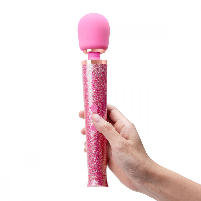 A hand holds onto the petite Le Wand All That Glimmers Wand Massager. The person's hand takes up about half of the wand massager's handle in its petite size. | Kinkly Shop