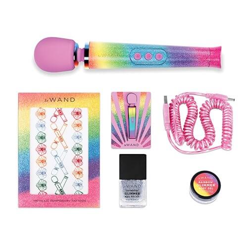 Everything included with the Le Wand Rainbow Ombre Petite Wand Massager laying out against a white background. It includes the petite wand massager, temporary tattoos, an enamel pin, the sparkly pink charging cable, glittery nail polish, and rainbow glimmer body gel. | Kinkly Shop