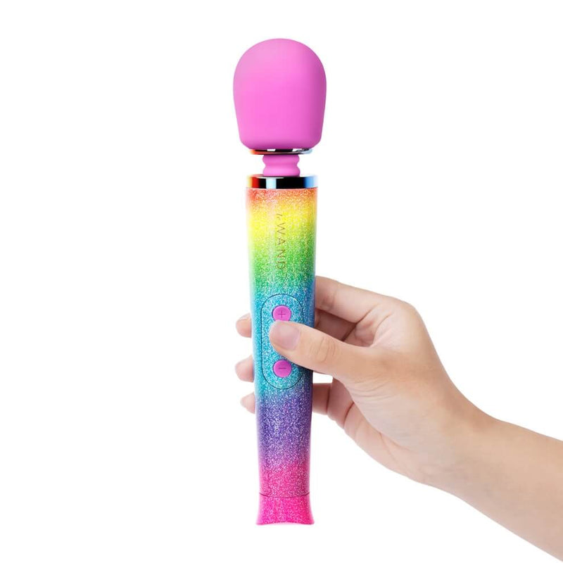 A hand holds the Le Wand Rainbow Ombre Petite Wand Massager. The wand massager looks much shorter and skinnier than most wand massagers. It is clearly longer than the person's hand, but it wouldn't be as long as their forearm. | Kinkly Shop