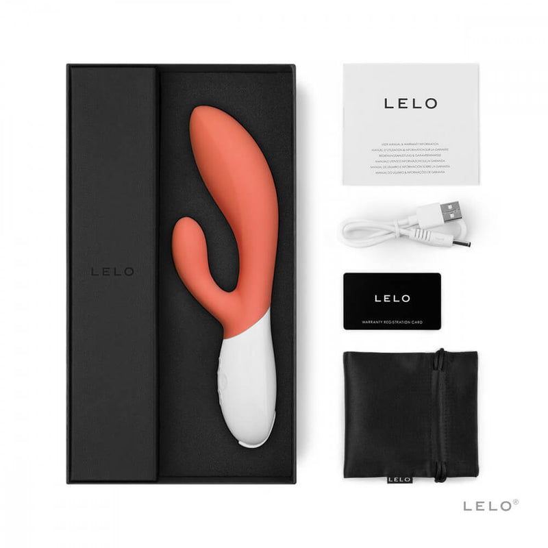 The LELO Ina 3 resting inside of its foam insert in its packaging. All of its accessories are sitting out around the open box including the instruction manual, the charging cable, the warranty registration card, and the drawstring storage pouch. | Kinkly Shop