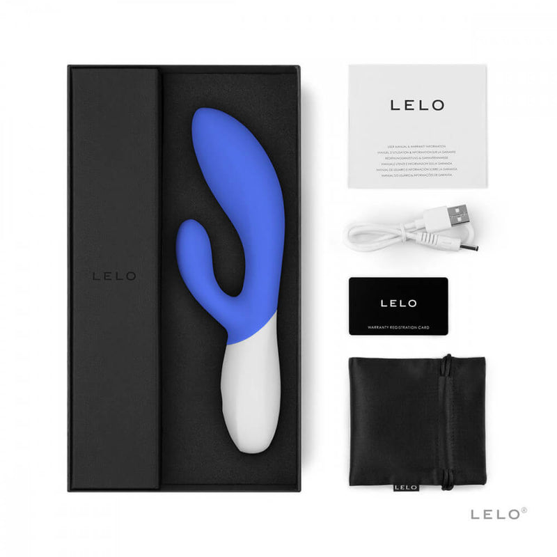 The LELO INA Wave 2 in Cali Sky Blue sits in its packaging in its molded tray. All of its accessories are sitting out next to the toy's tray which includes the instruction manual, the charging cable, the warranty card information, and the drawstring storage bag. | Kinkly Shop
