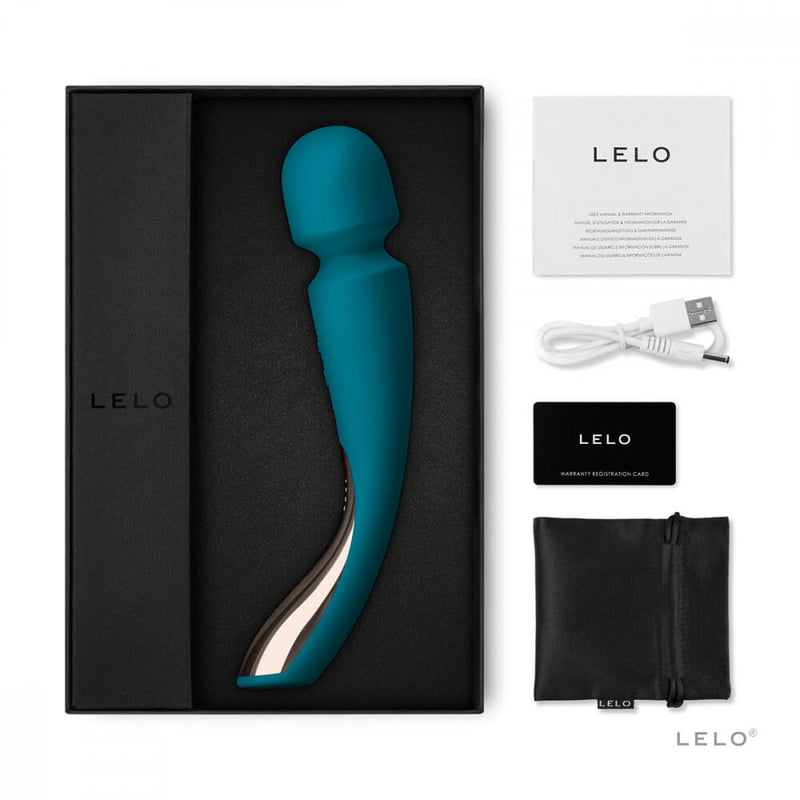 The LELO Smart Wand 2 Medium sits in its foam tray within its packaging. Next to the open box, everything that comes with the LELO Smart Wand 2 Medium is displayed including the instruction manual, the charging cable, the warranty card information, and the drawstring bag. | Kinkly Shop