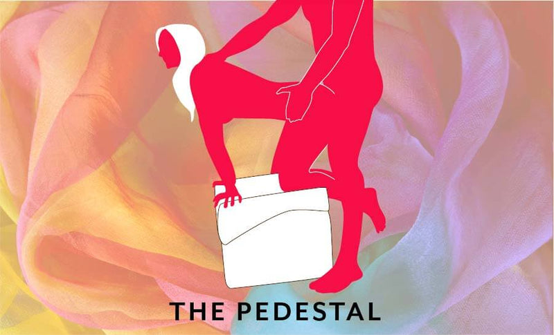 An illustrated image of the Liberator Flip Ramp folded up called "The Pedestal". The receiving partner is on their knees on top of the folded up, square-shape Liberator Flip Ramp. The penetrating partner is standing behind them to penetrate them from behind. The position looks precarious and requires a lot of balance to achieve. | Kinkly Shop