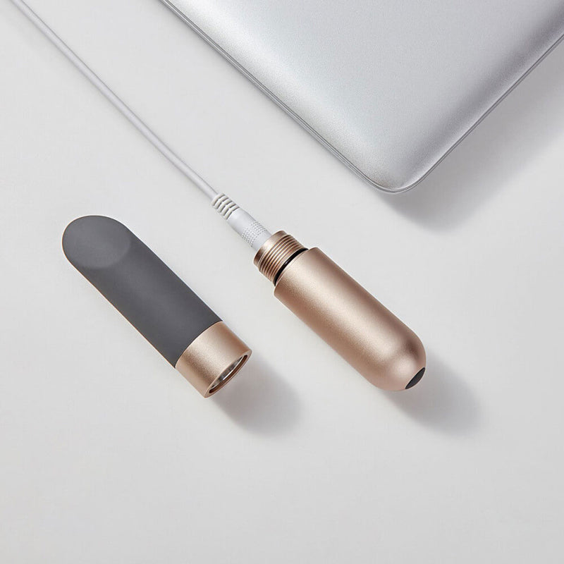 The battery base has been unscrewed from the Love Not War Amore. The battery is plugged into the charger while the Love Not War Amore tip is sitting next to it. | Kinkly SHop