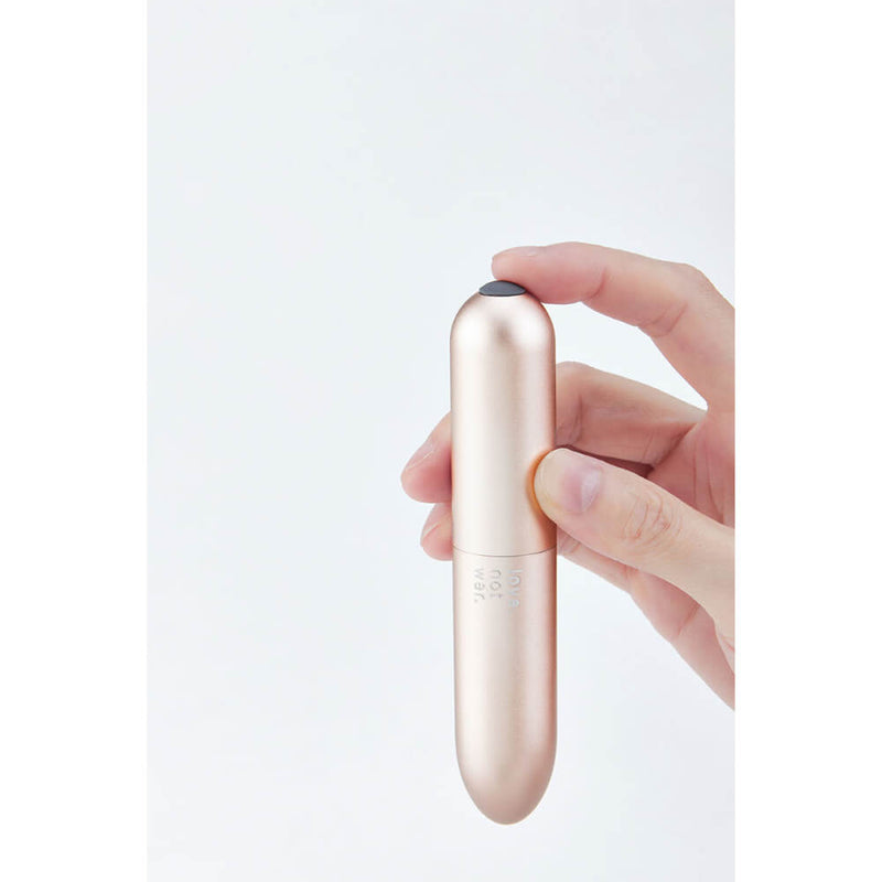 A hand holds the Love Not War Maya. A fingertip is about to press down on the single button at the base of the vibe to control the vibrations while the rest of the fingers provide grip around the vibrator's length. | Kinkly Shop