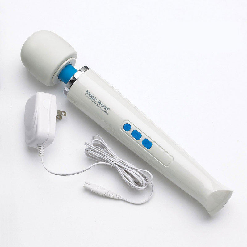 The Magic Wand Rechargeable laying diagonally in the image. The charging cable is laying next to it. Unlike the Original Magic Wand, the charging cable is unplugged, allowing the toy is be used without being attached to a cord. | Kinkly Shop