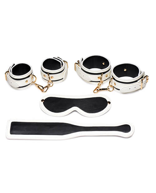 Master Series Kink in the Dark Set shown during the daylight. All of the items look black with white trim lining them. The image shows all four cuffs, the blindfold, and the paddle laid flat. | Kinkly Shop
