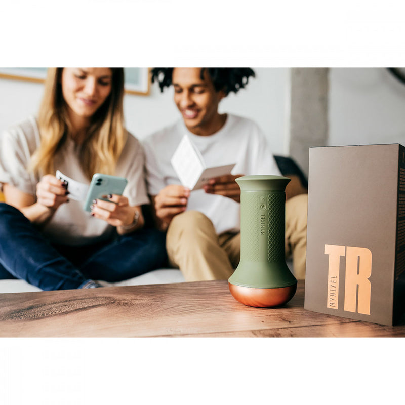 Two people sit together smiling on a couch while they both are watching a cell phone where the MyHixel TR app is being installed. The MyHixel TR premature ejaculation sex toy sits next to the open packaging on the table in front of them. | Kinkly Shop