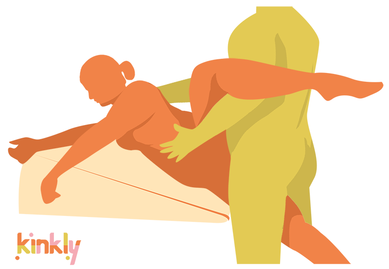 An illustrated sex position. It shows the Liberator Ramp pulled up to the edge of a bed. The receiving partner is laying, on their side, along the length of it. Their leg is in the air. The penetrating partner straddles their lower leg while getting close for penetration. | Kinkly Shop